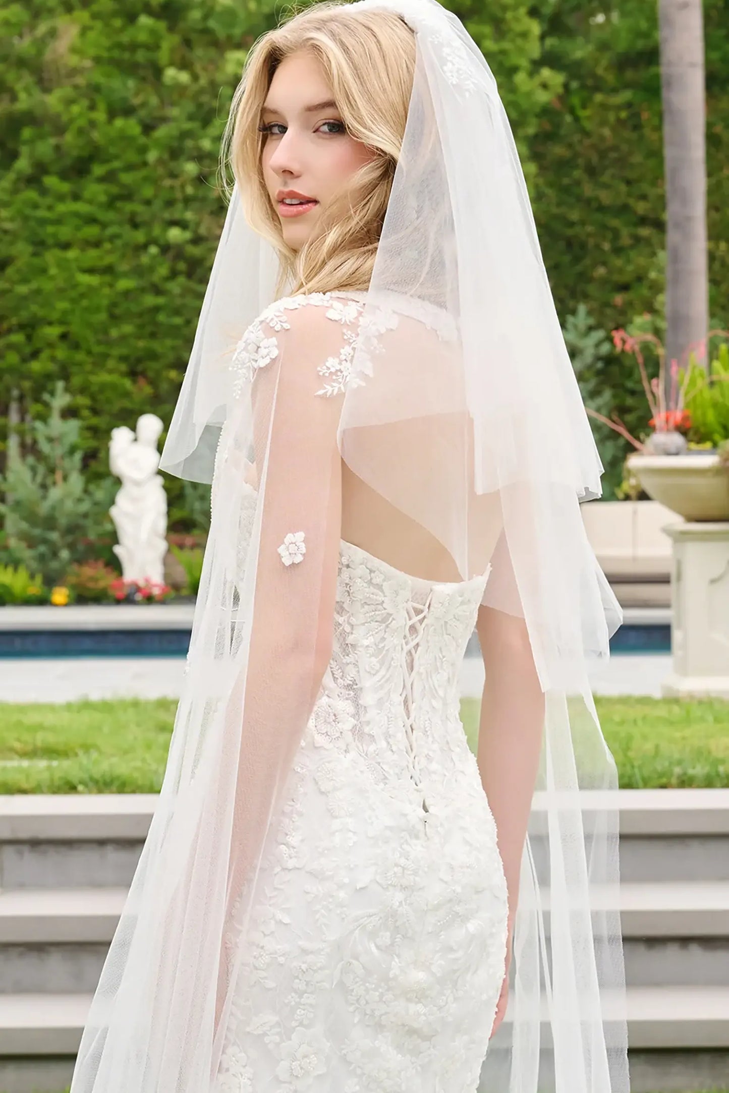 Off-white wedding dress styled with detached cape sleeves and short veil