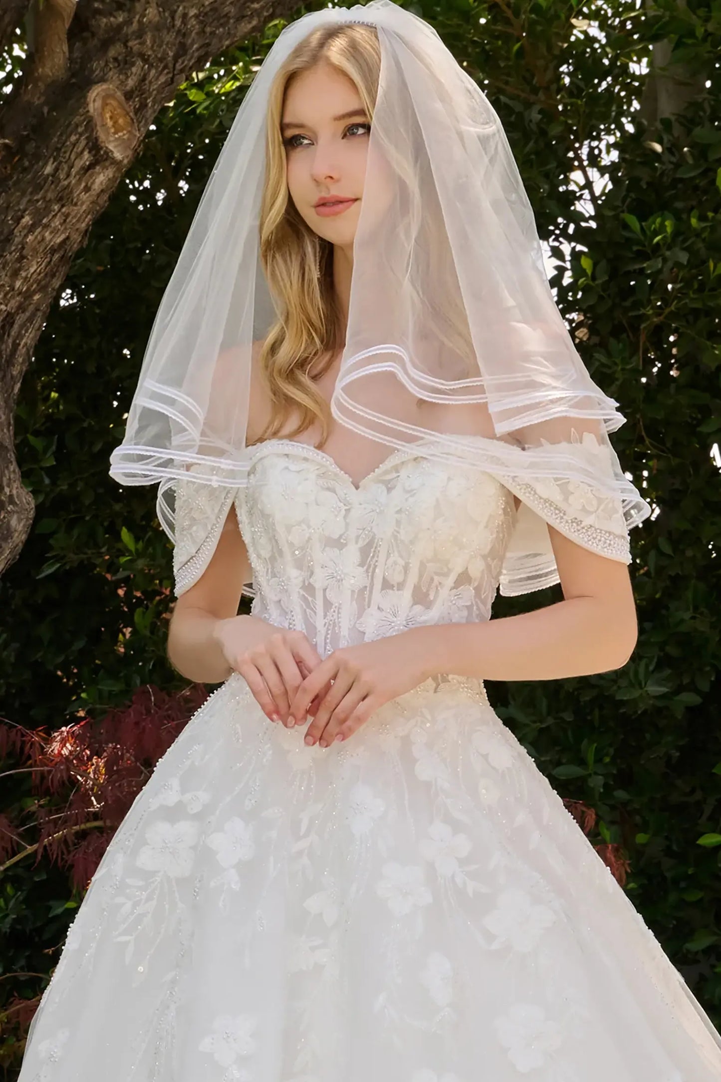 Off-white wedding dress completed with short veil coordinating with the gown design