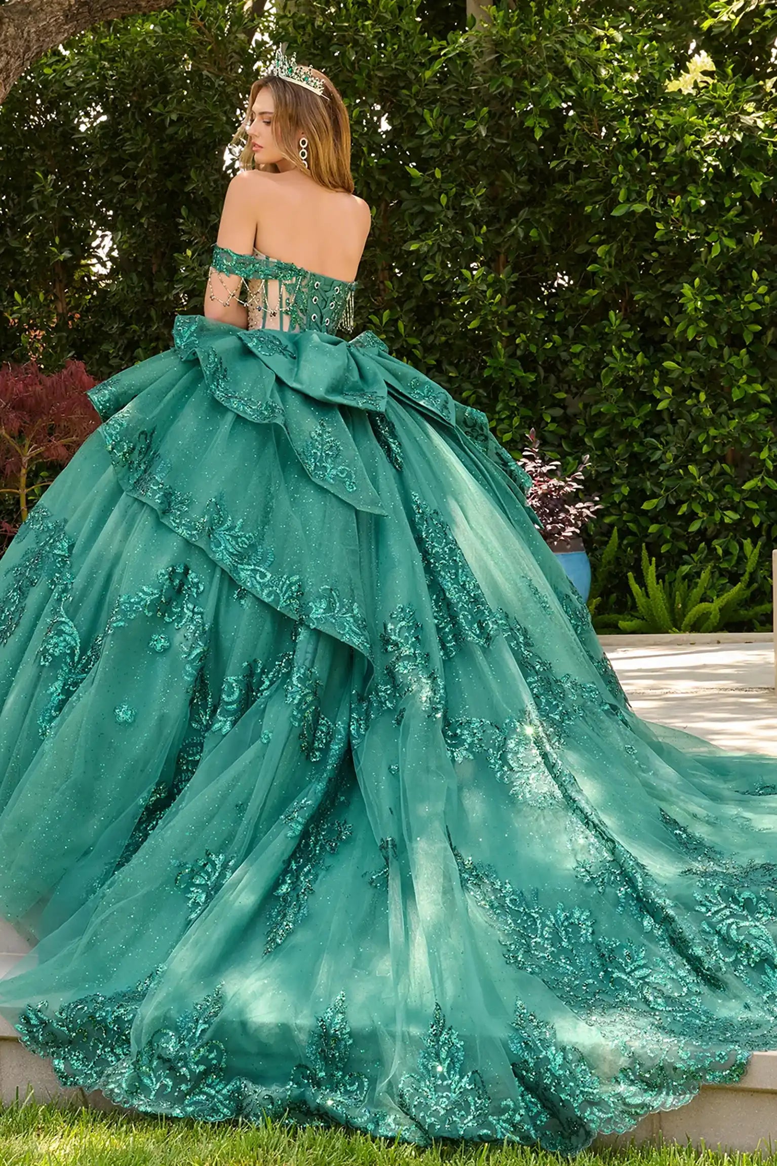 Green quinceañera ball gown with bejeweled grommets, glitter underlayer and dramatic train finish