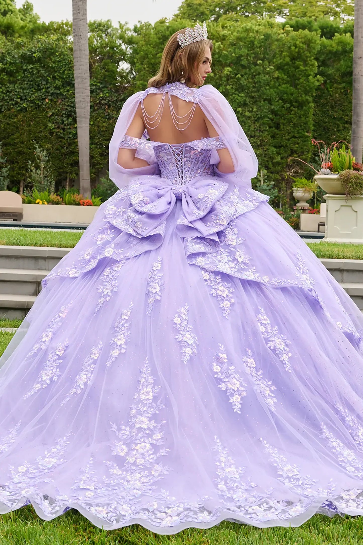 Lilac quinceañera ball gown with lace-up back corset and cascading overskirt flowing over skirt and train for volume