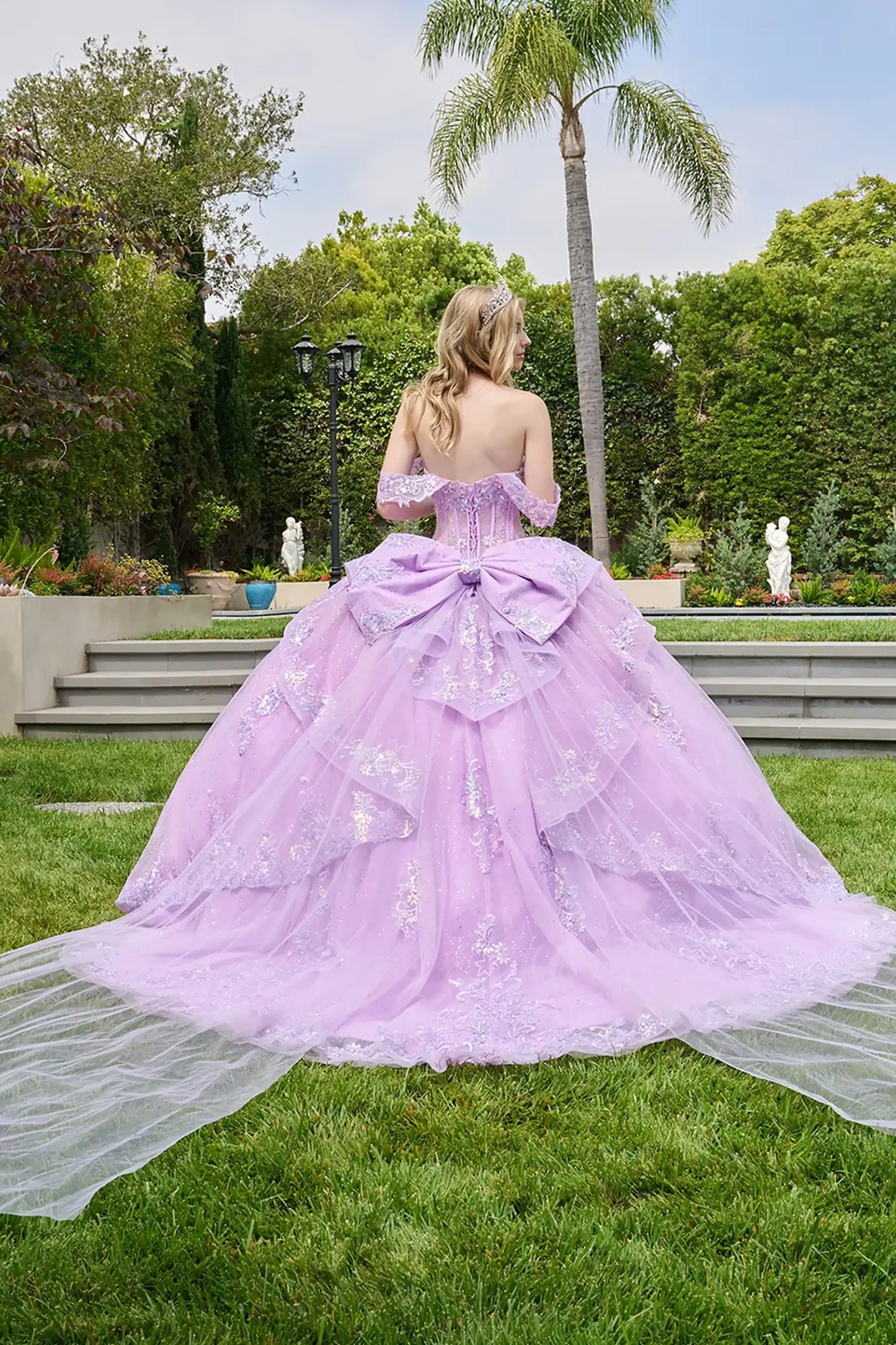 Lilac quinceañera ball gown completed with detachable bow featuring train-like tails for elegance
