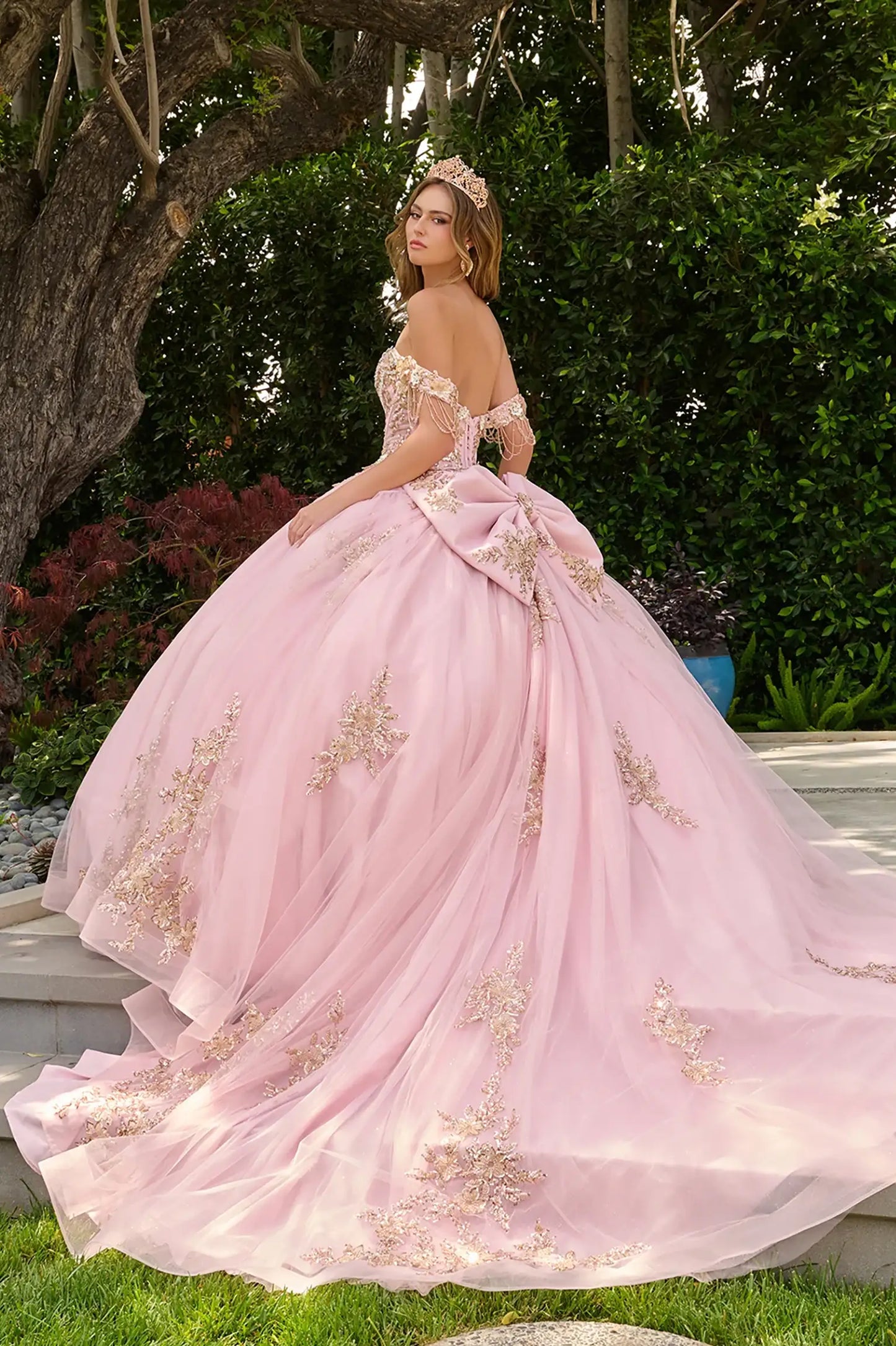 Blush quinceañera ball gown with voluminous skirt layered over glitter mesh underlayer and graceful train