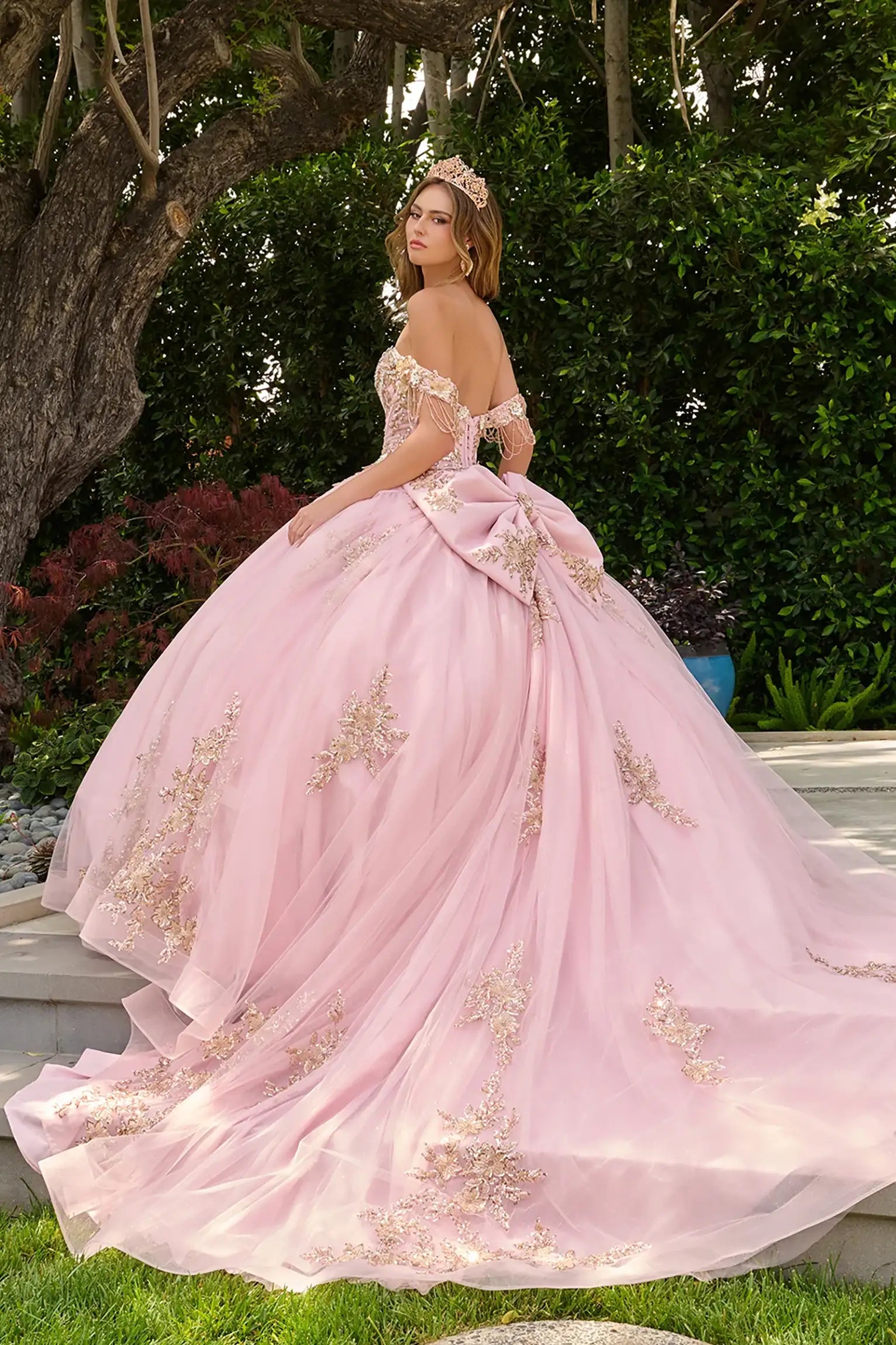 Blush quinceañera ball gown with voluminous skirt layered over glitter mesh underlayer and graceful train