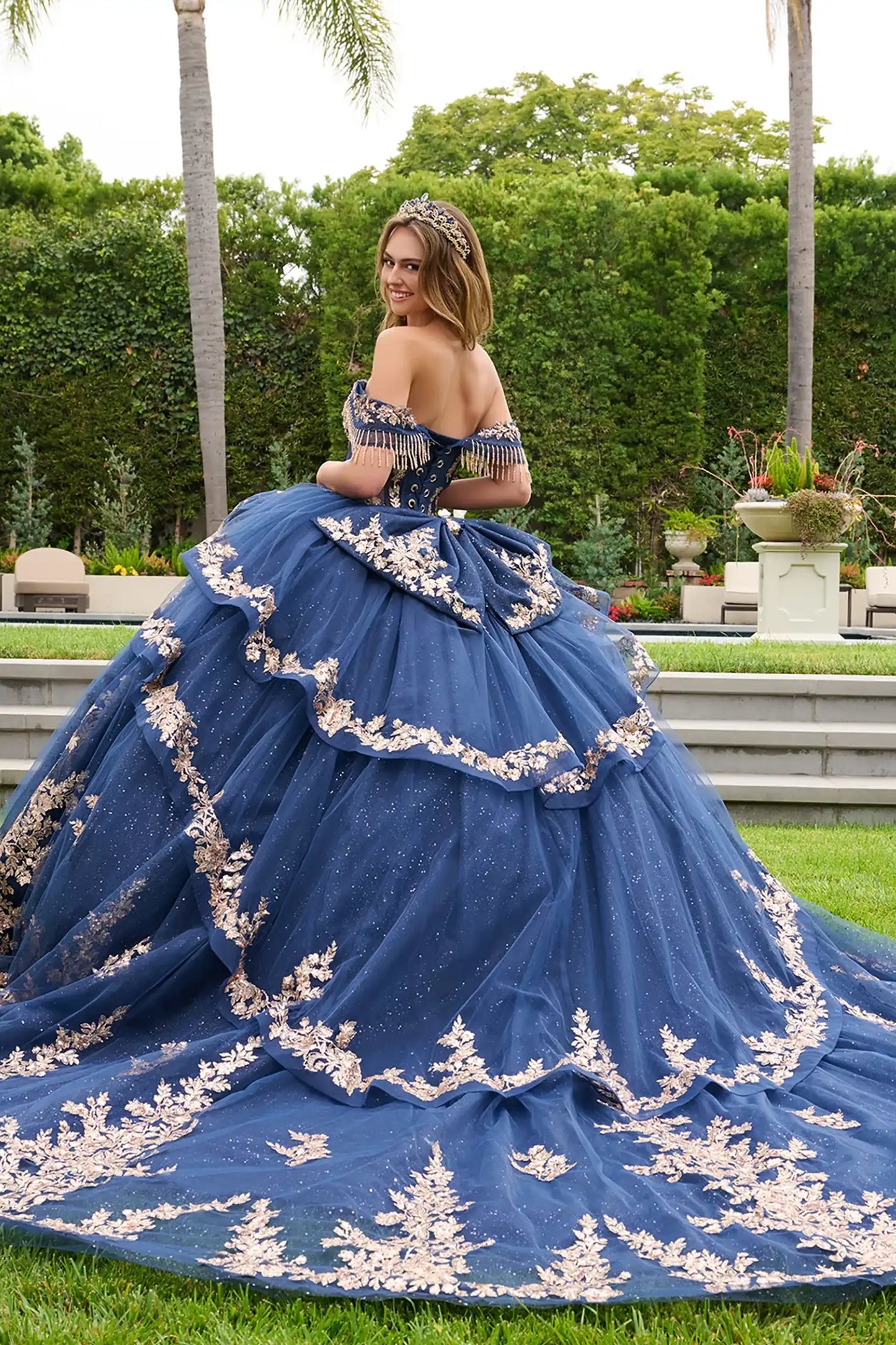 Navy quinceañera ball gown with high-low cascading overskirt layered over glitter mesh underlayer