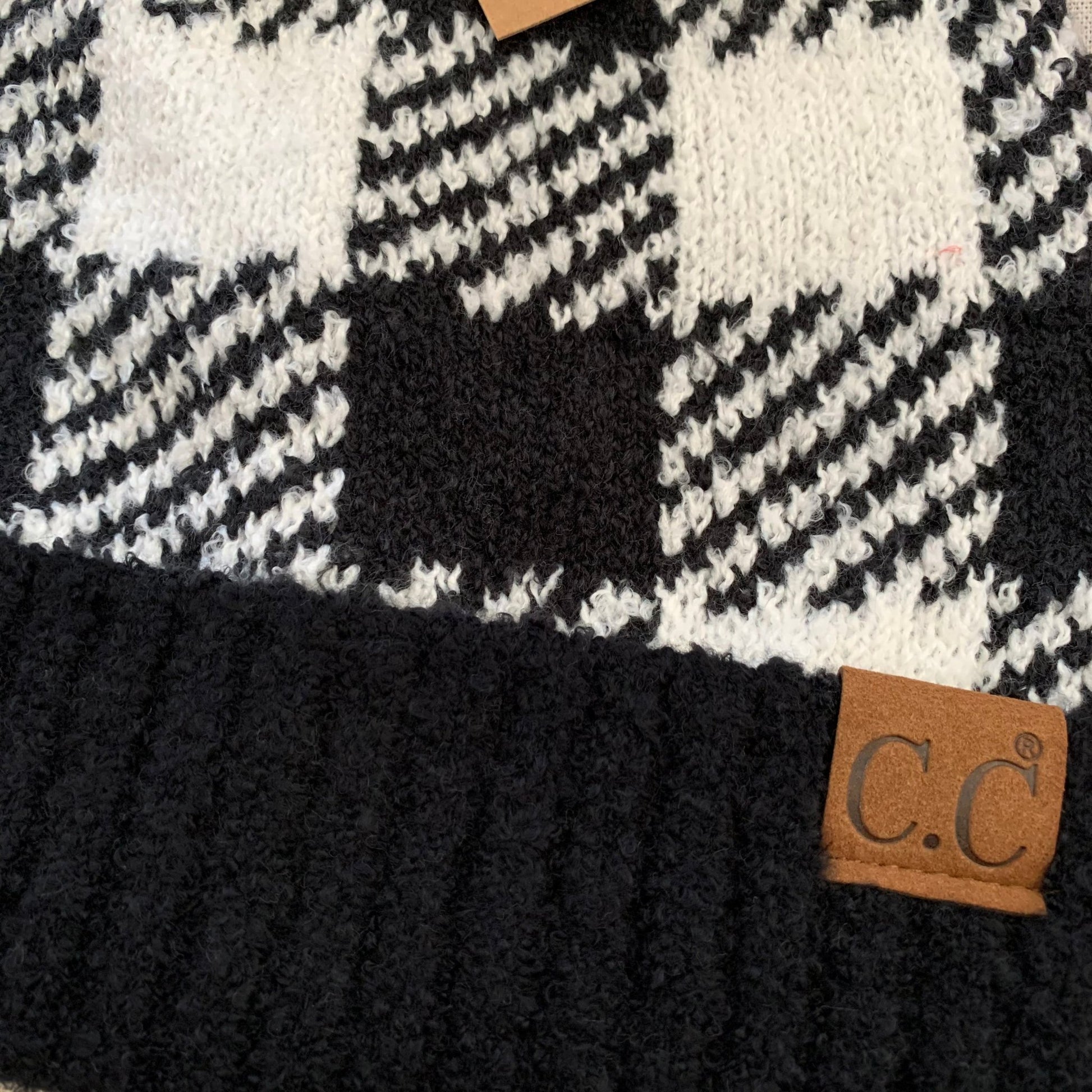 Black red plaid pom-pom women's winter beanie, close-up view.
