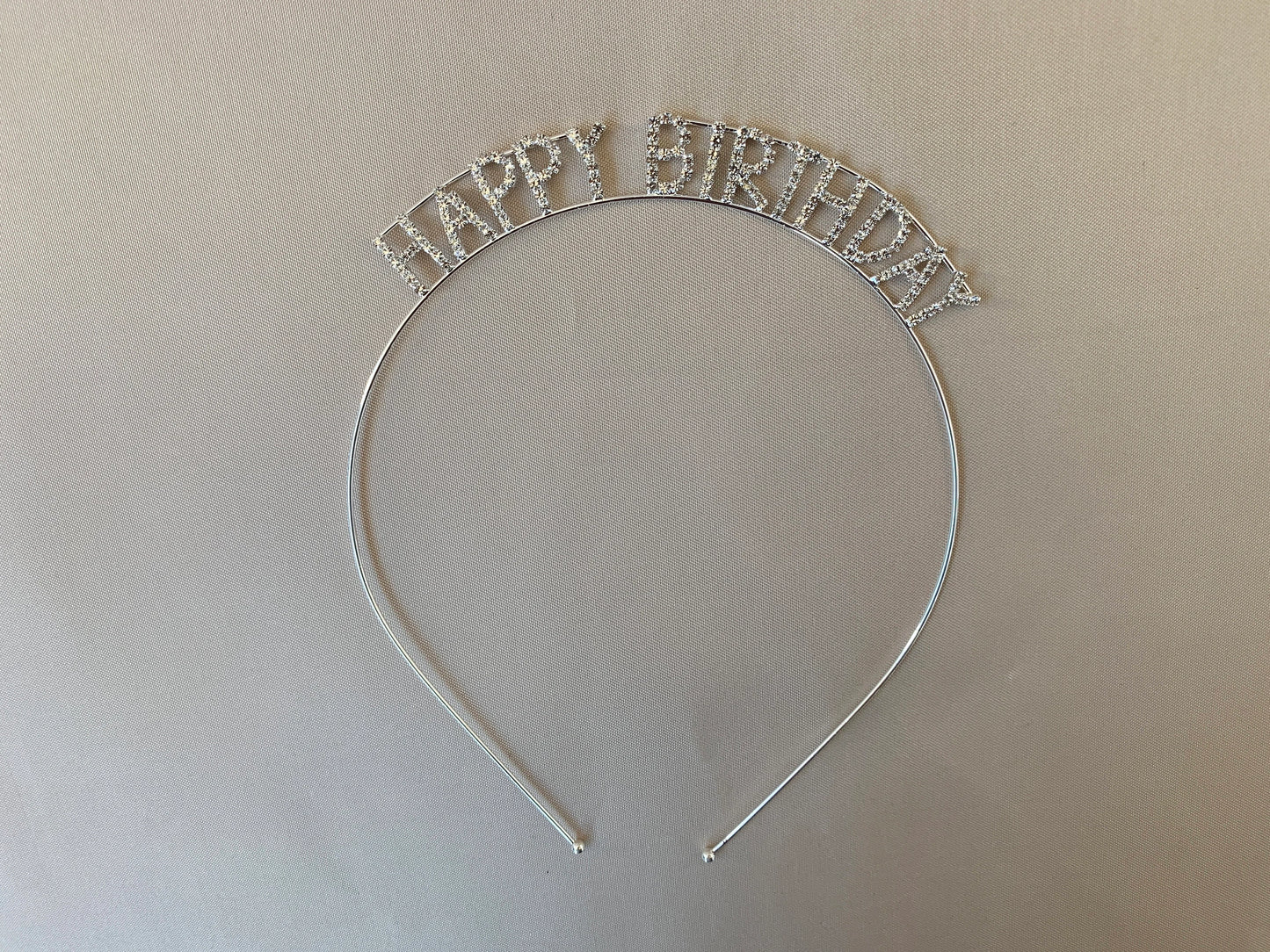 Silver 'Happy Birthday' headband on a beige background