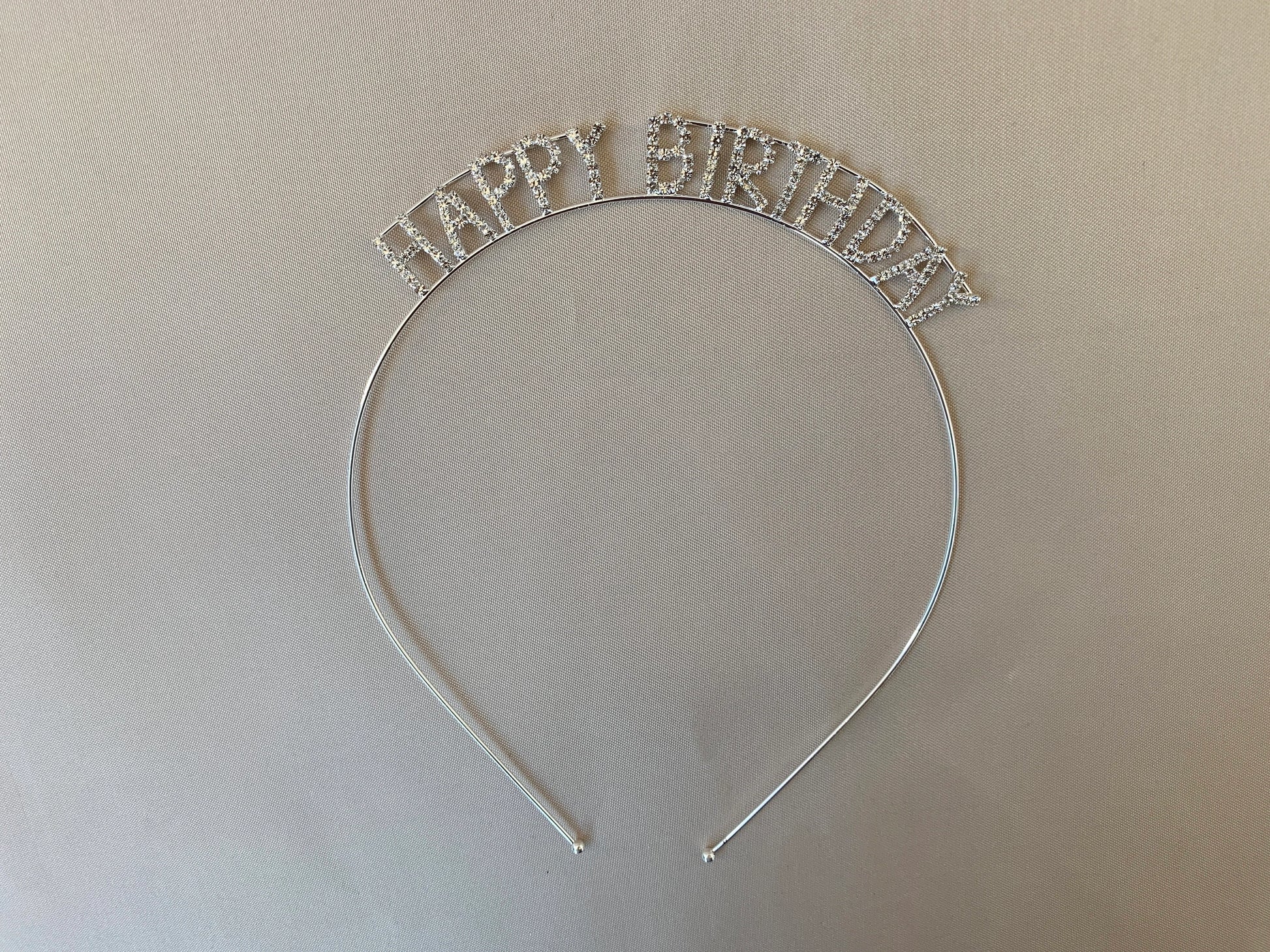 Silver 'Happy Birthday' headband on a beige background