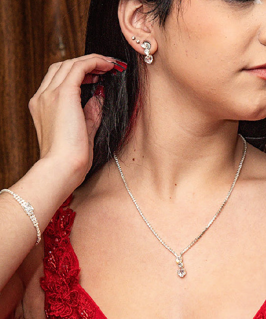 Girl wearing a silver rhinestone earring and necklace, with a blurred background