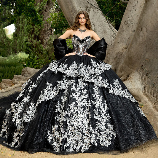 Woman in a black and white floral gown standing in a natural setting.