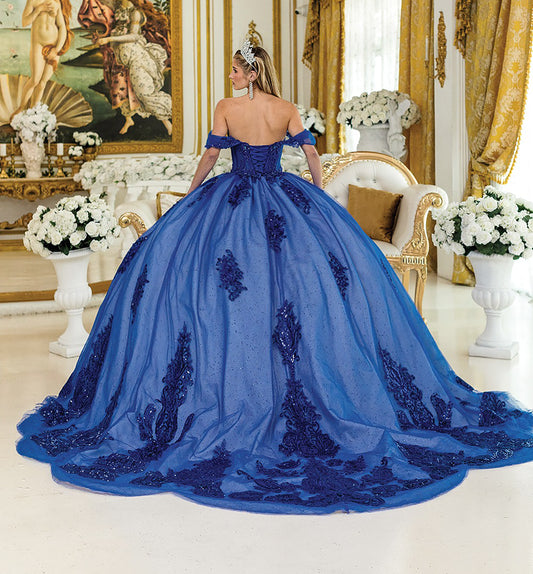 Woman in a blue evening gown with intricate detailing in an elegant room.