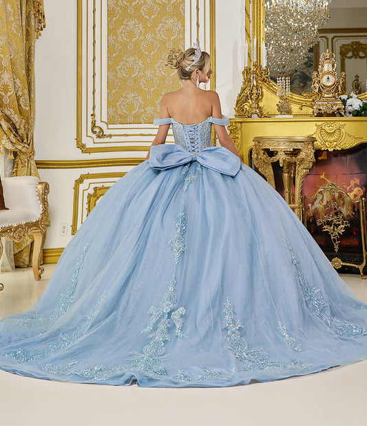 Woman in a light blue gown with a large bow in an ornate room.