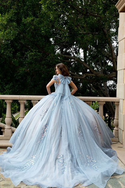 Woman in a light blue gown standing on a balcony with trees in the background