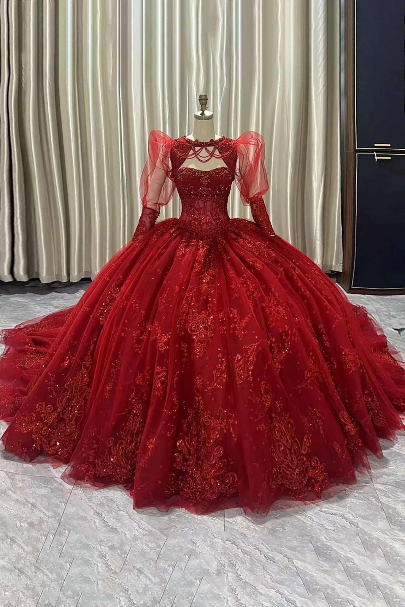Red lace ball gown on a mannequin against a neutral background