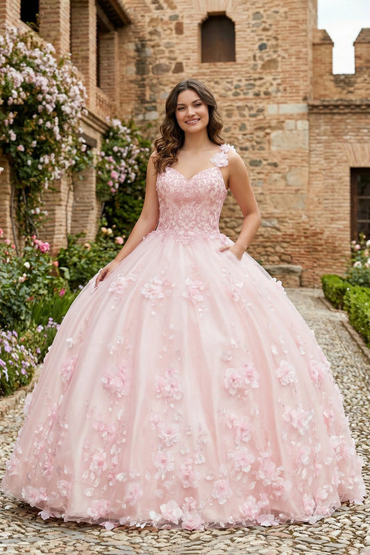 Girl in a pink floral quinceanera ball gown dress standing in front of a brick building with flowers.