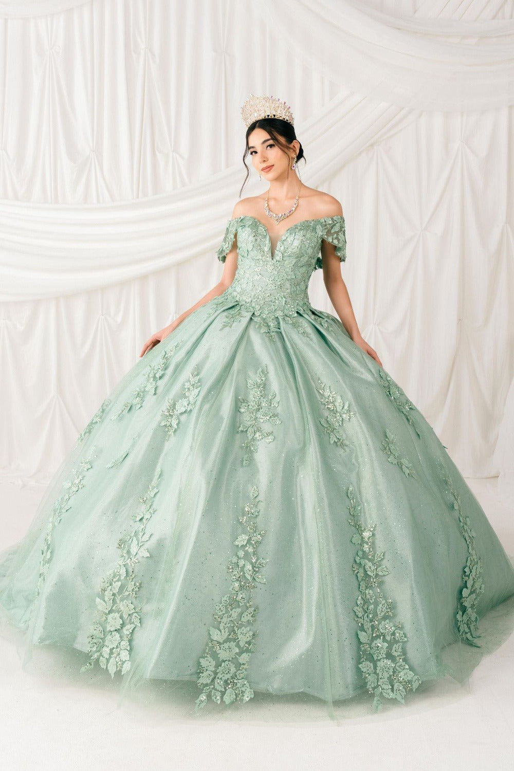 Woman in a green ball gown with floral details against a white background