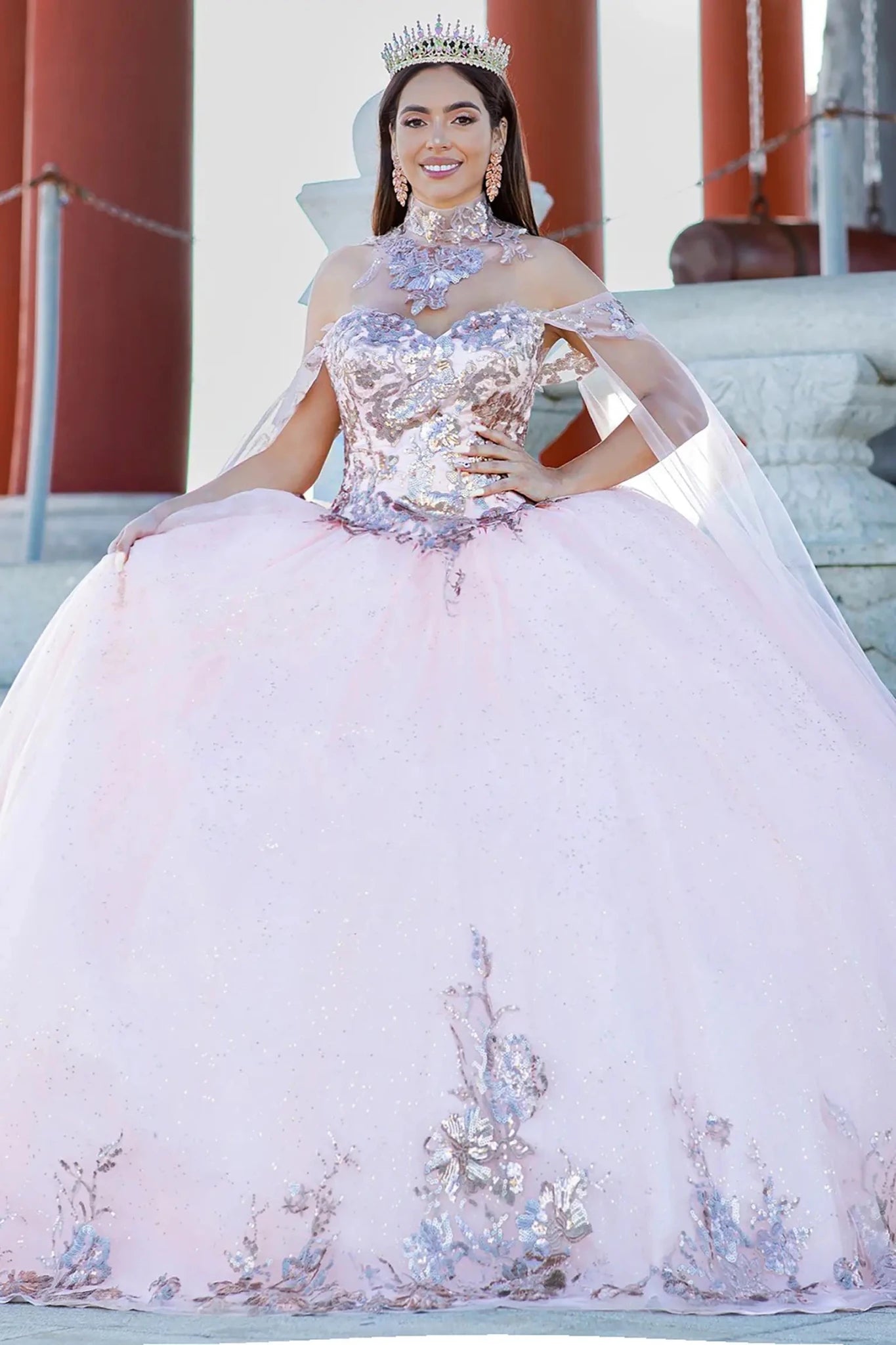 Woman in a pink and pink-silver sequin quinceañera dress with a tiara, standing outdoors.