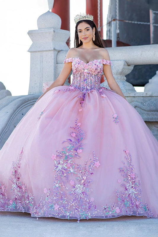 Woman in a pink and purple floral quince dress with a tiara, standing in front of classical architecture.