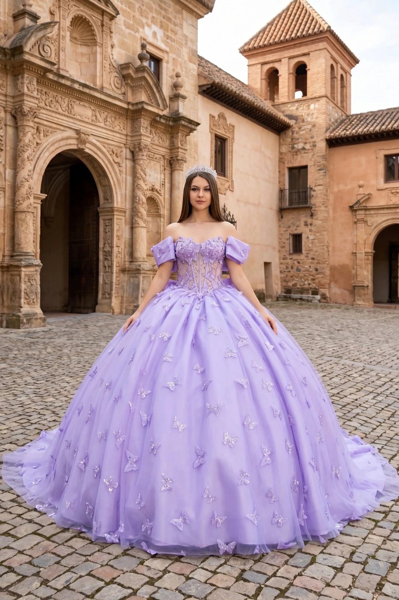 Woman in a lilac quinceanera ball gown with 3D butterflies standing in front of a historic building.