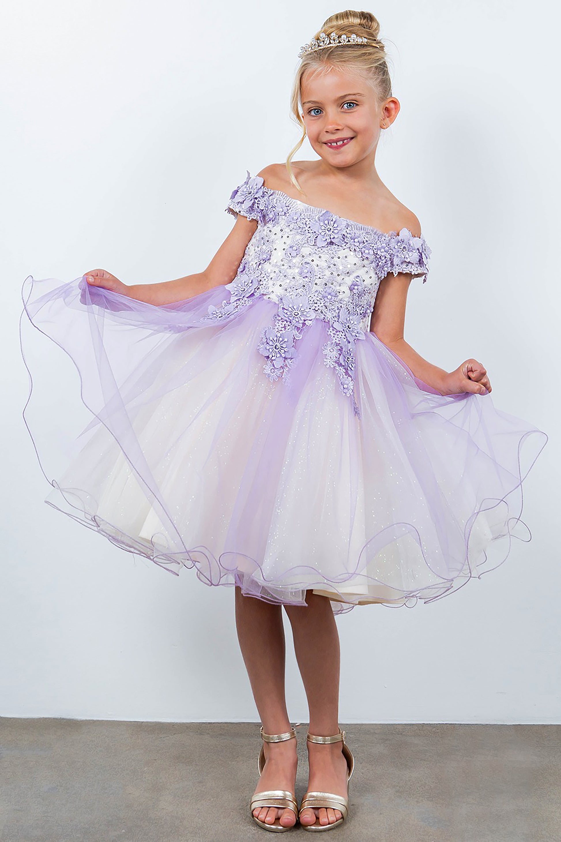 Young girl wearing a lilac dress with sequin details against a plain background