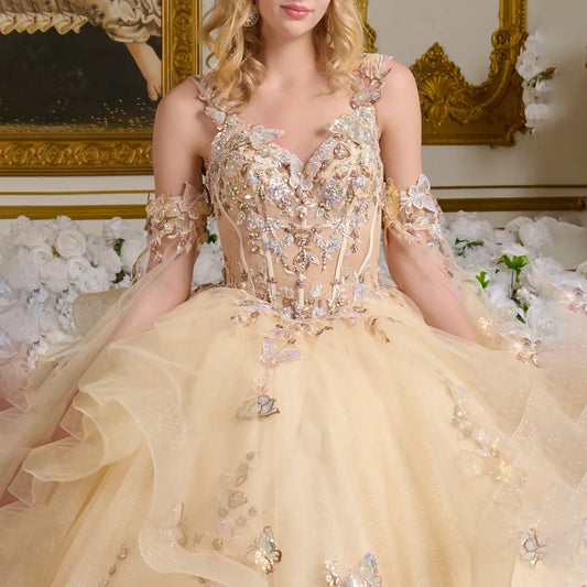 Woman wearing a beige evening gown with floral and butterfly details in an elegant indoor setting.