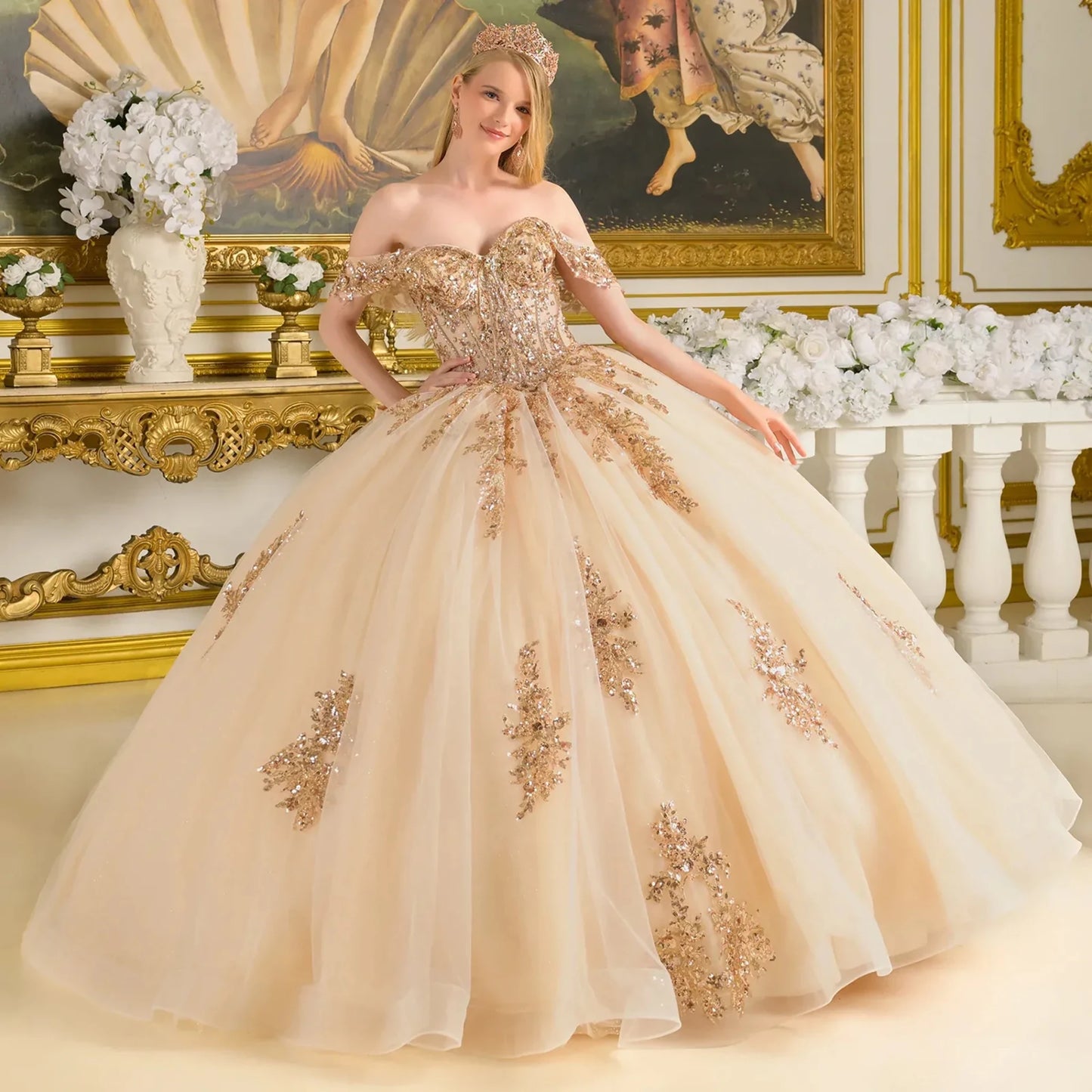 Woman in a beige and gold quince ball gown in an ornate room with floral decorations.