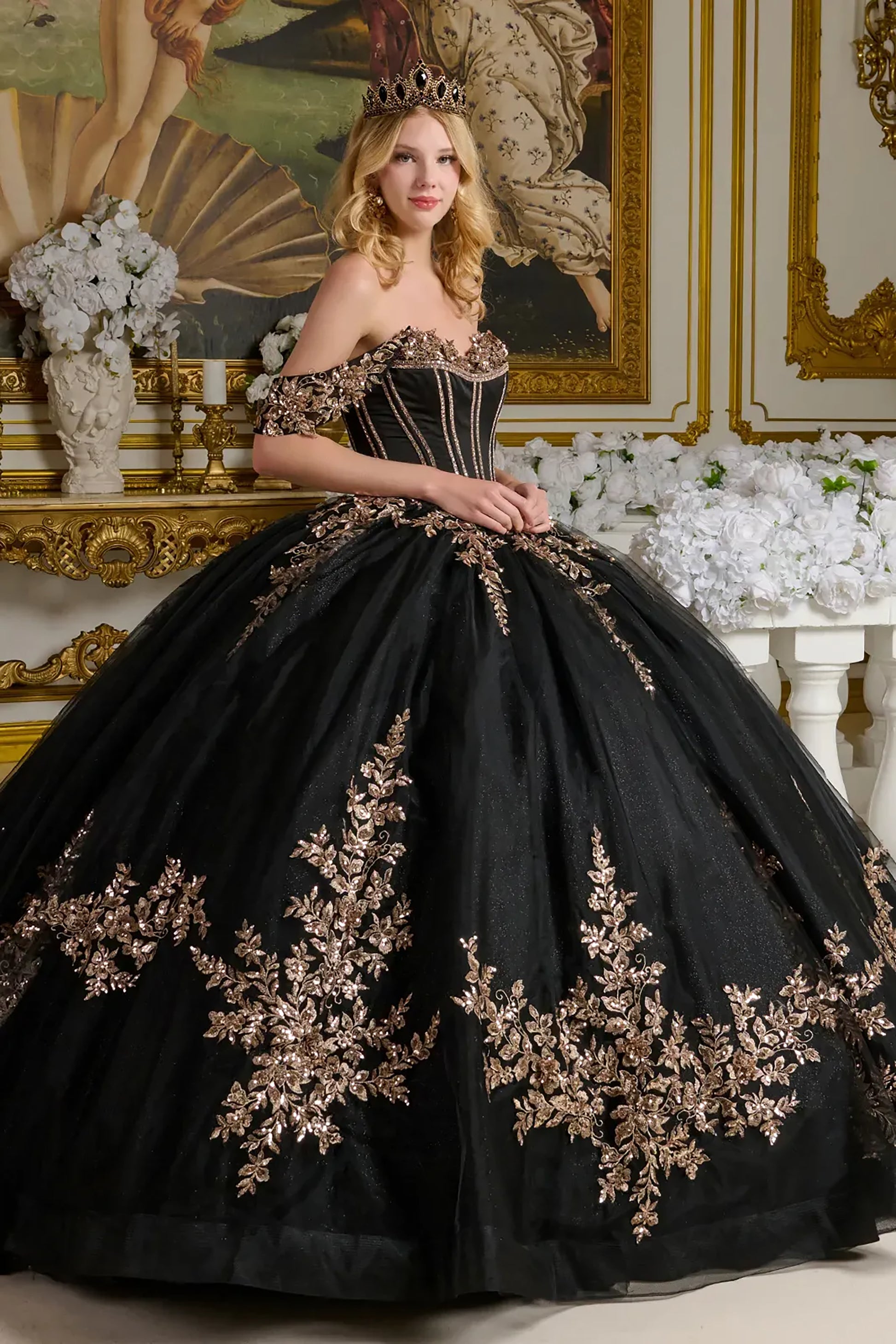 Woman in a black ball gown with gold embroidery in an ornate room.