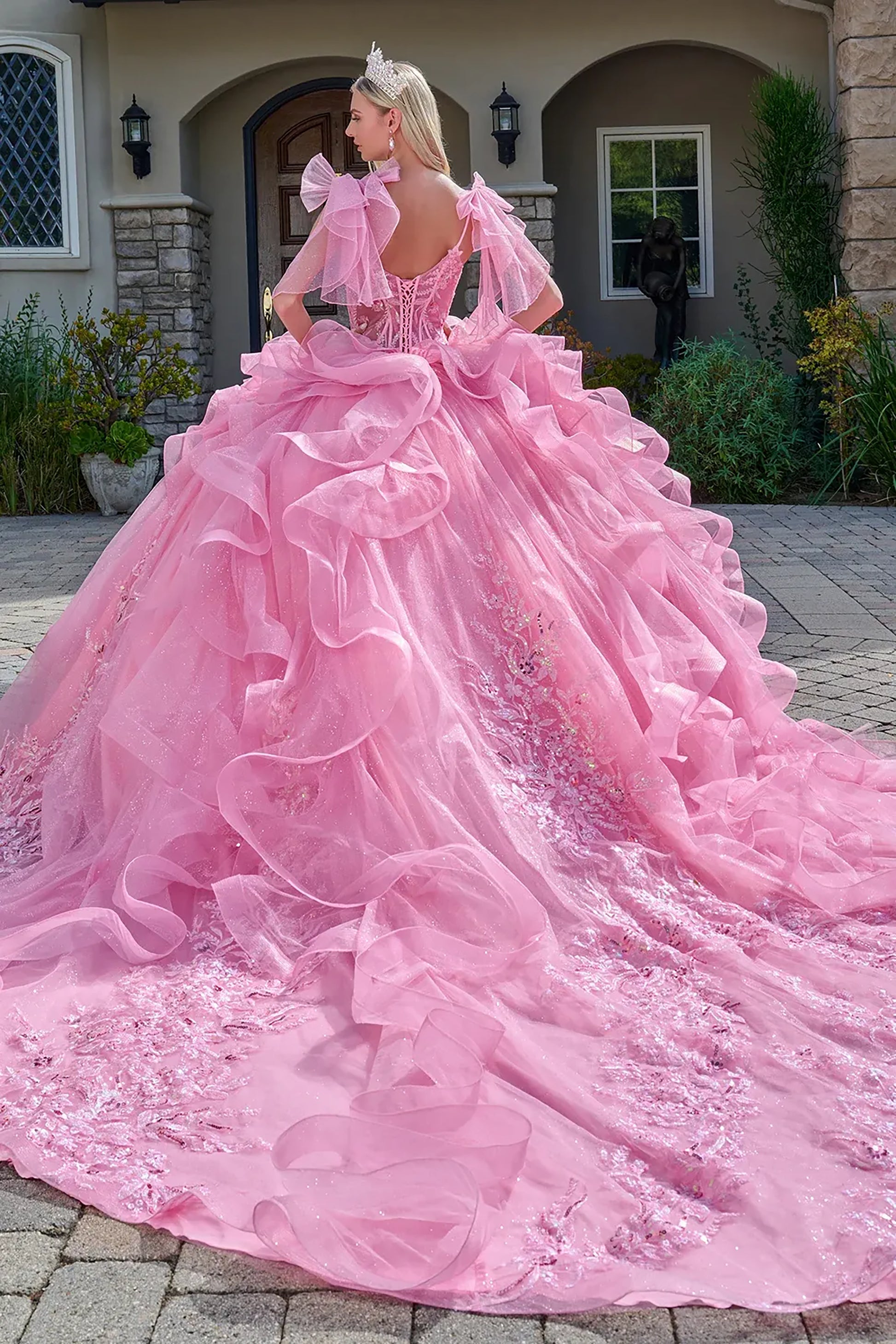 Woman in a pink ball gown standing in front of a house.