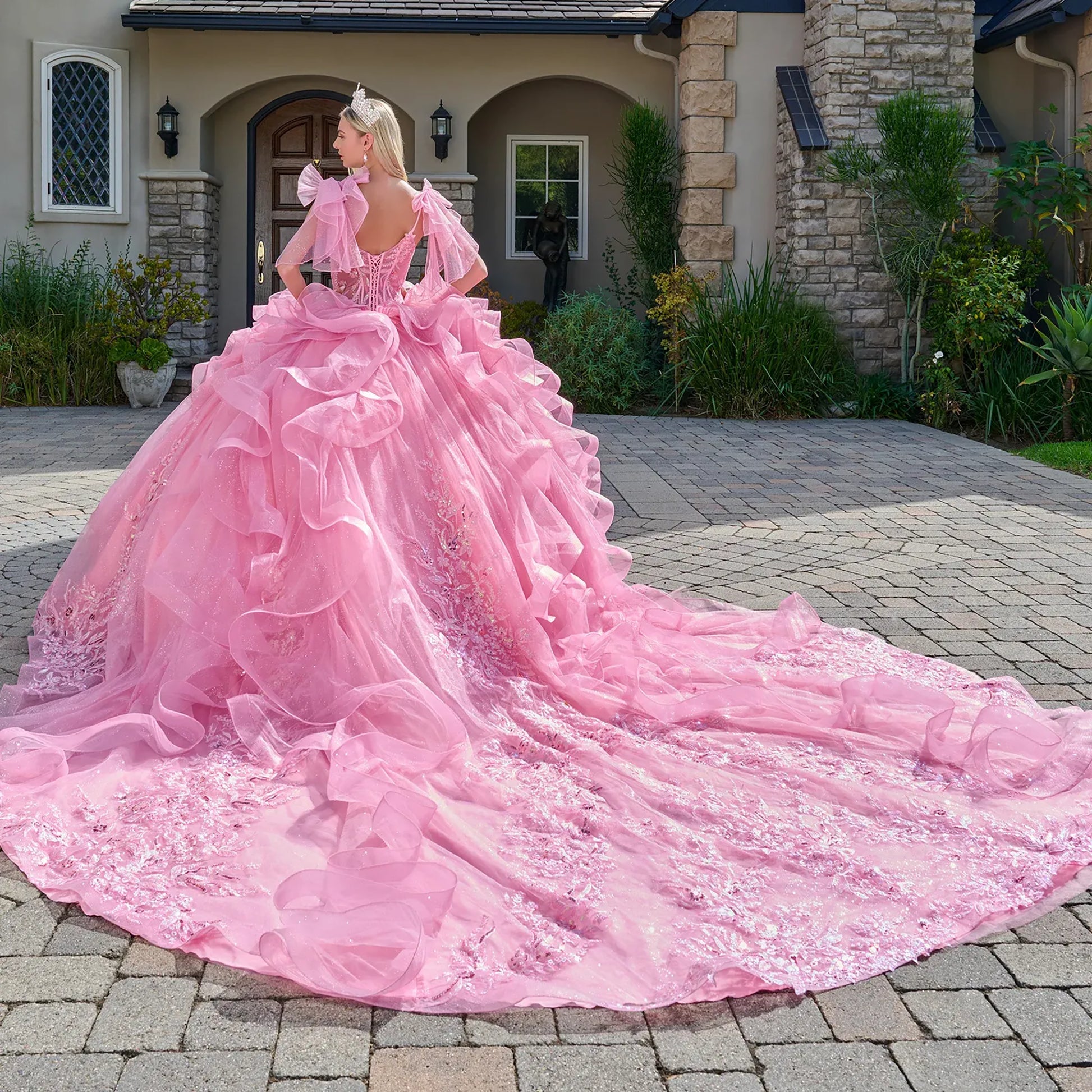 Woman in a pink wedding dress standing outdoors on a driveway.