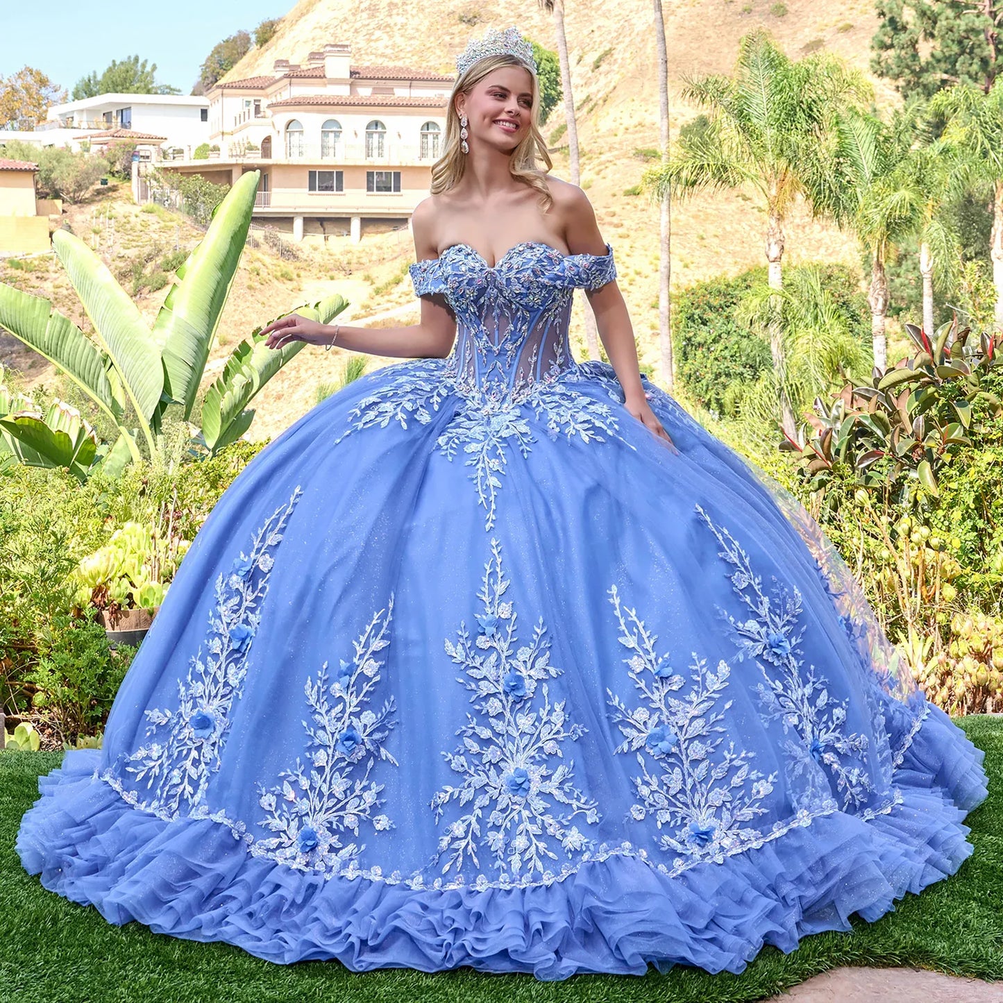 Woman in a dusty blue quince  ball gown with floral embroidery standing outdoors.