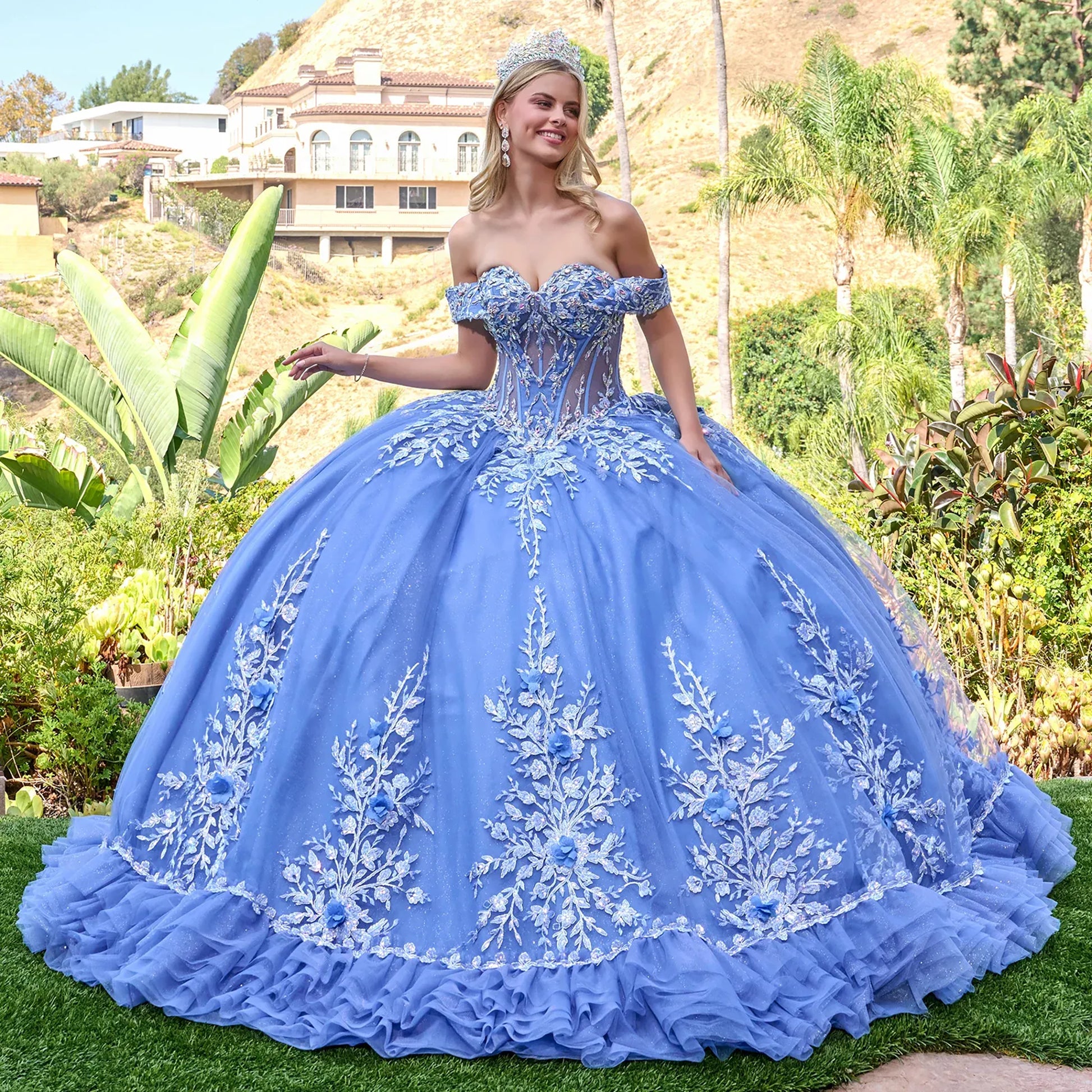 Woman in a dusty blue quince  ball gown with floral embroidery standing outdoors.