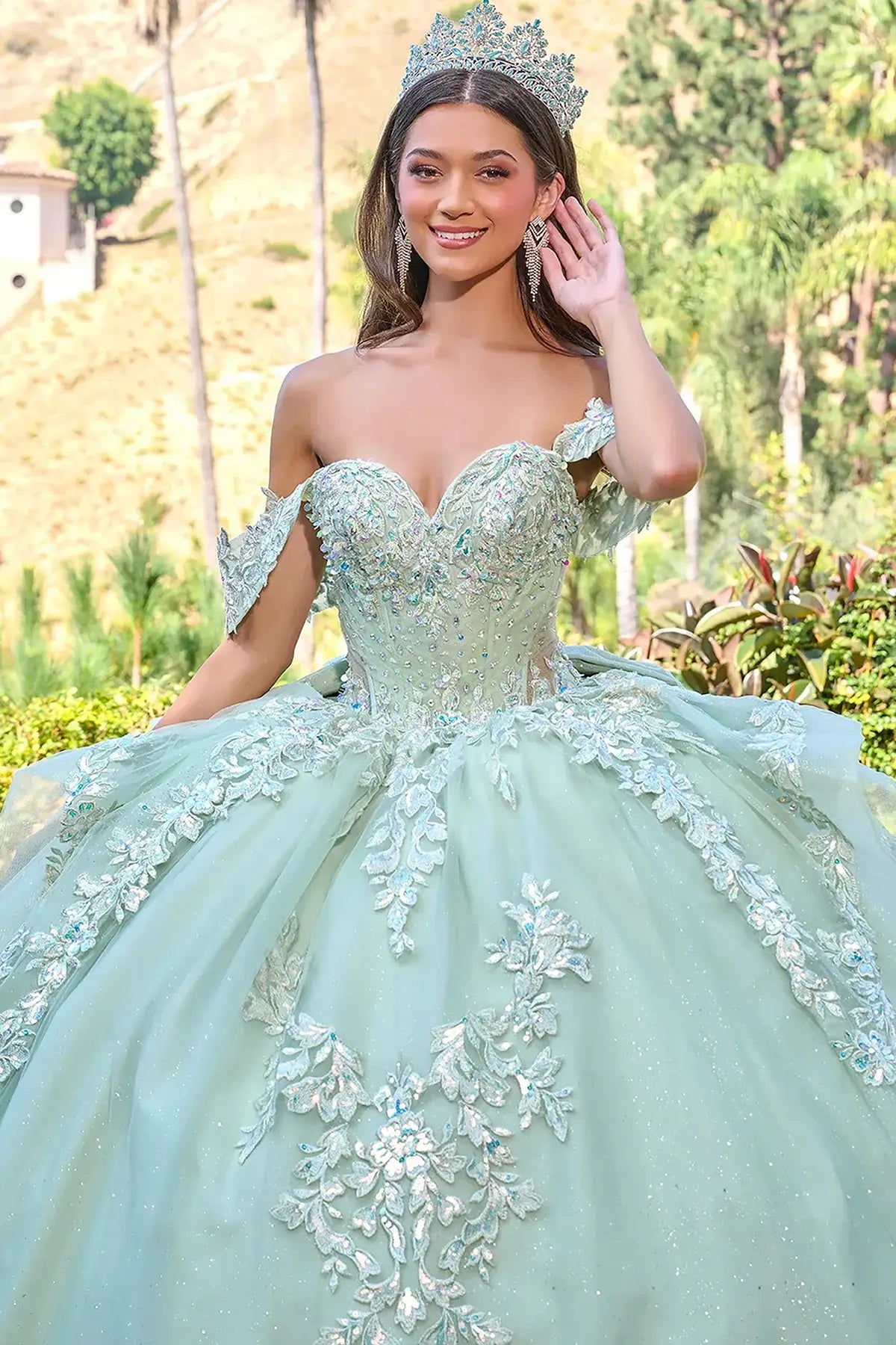 Woman in a sage green quinceañera dress with floral details and sweet heart neckline outdoors 