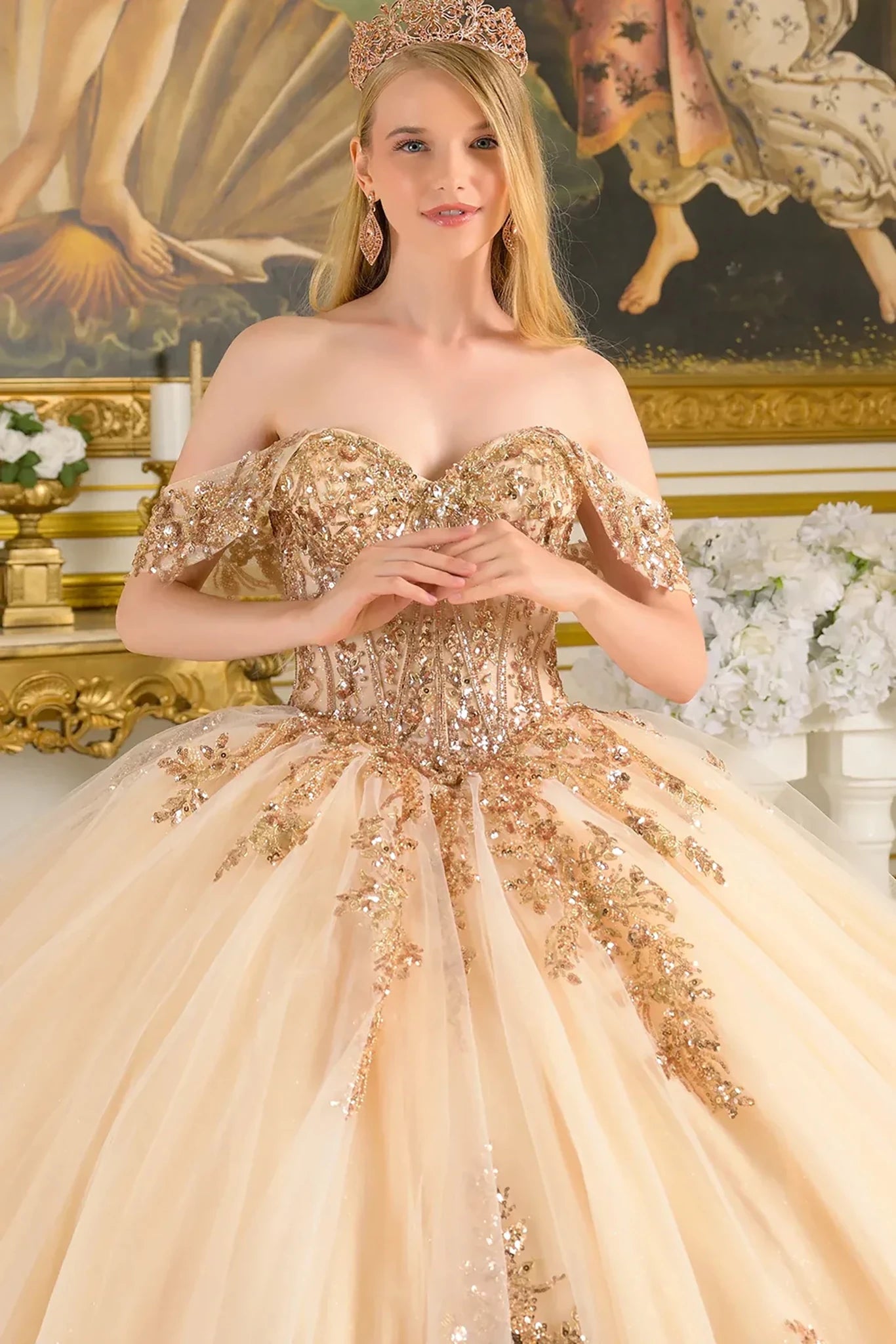 Woman in a gold and beige gown with intricate detailing in an ornate setting.