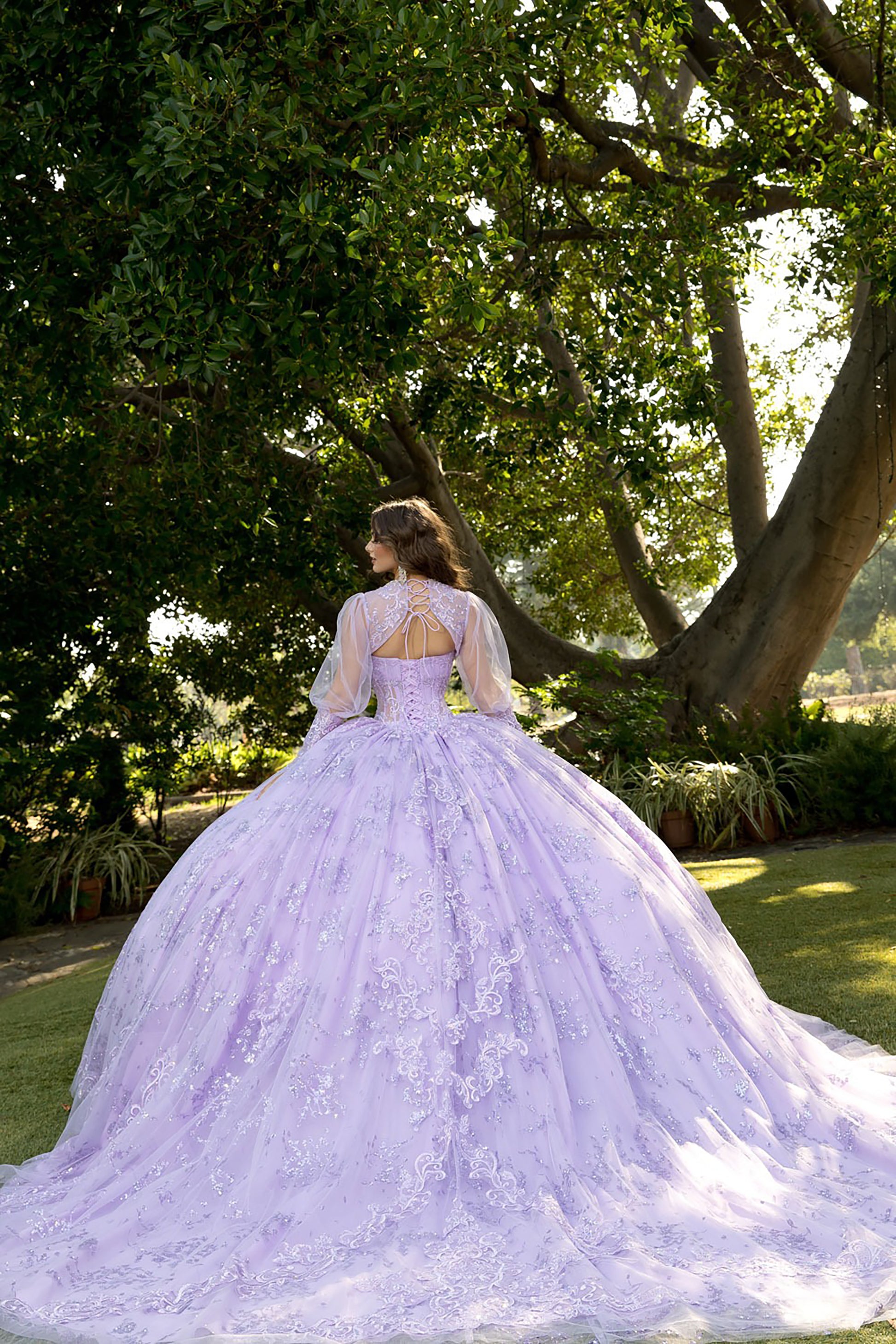 Woman in a lavender wedding dress standing in a park with trees and greenery.