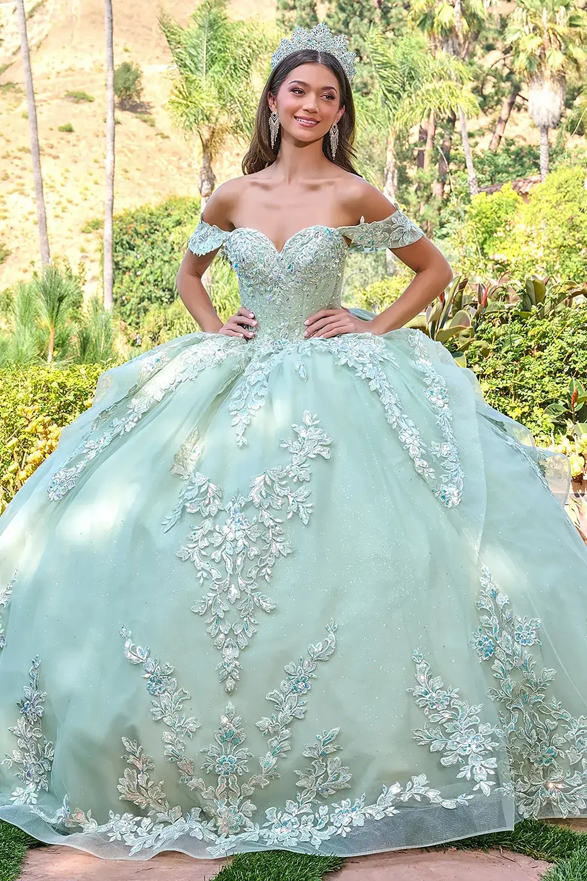 Woman in a light green quinceañera dress with floral embroidery outdoors.