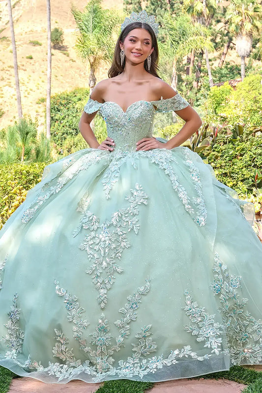 Woman in a light green quinceañera dress with floral embroidery outdoors.