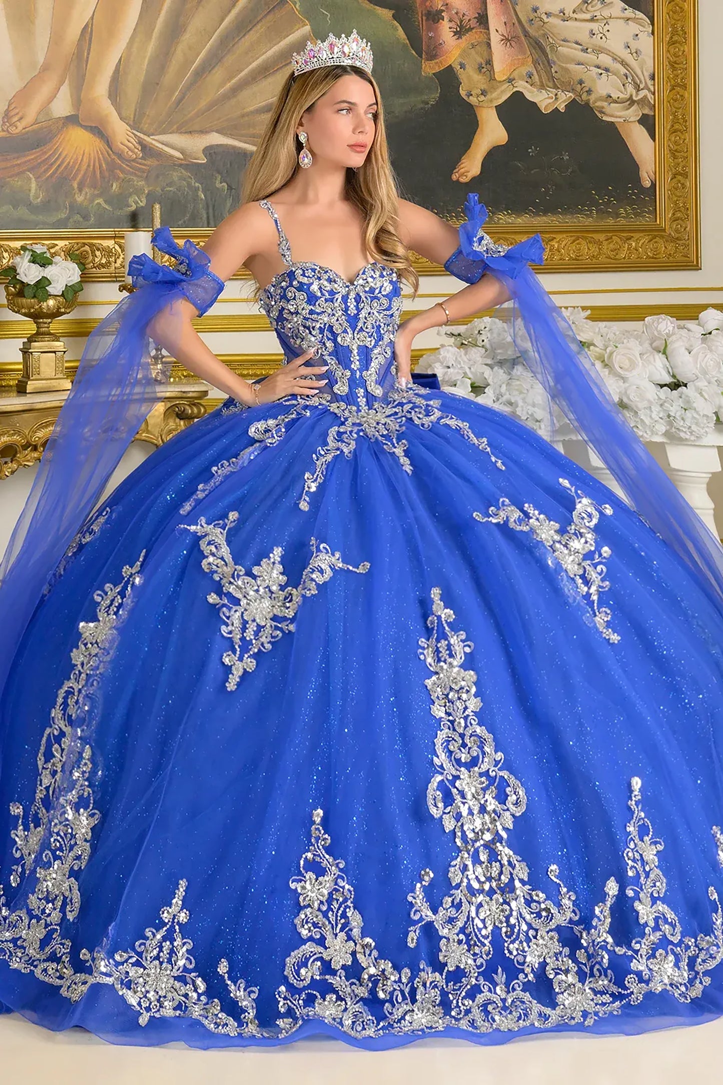 Woman in a blue ball gown with silver embroidery in an elegant room.