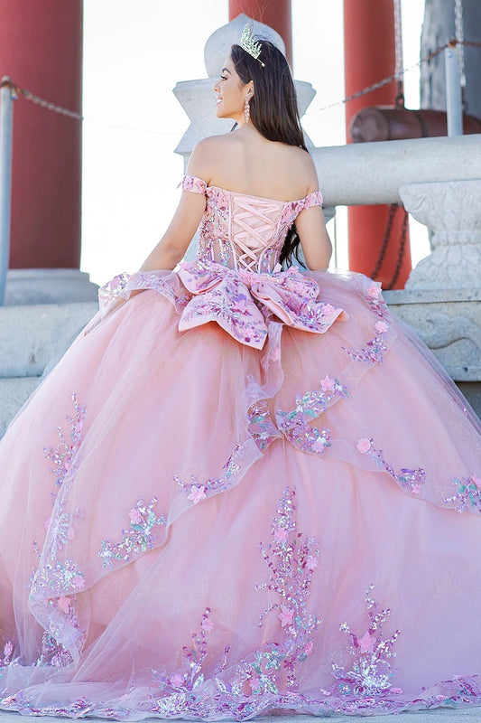 Pink ball gown with floral details worn by a person, standing outdoors.