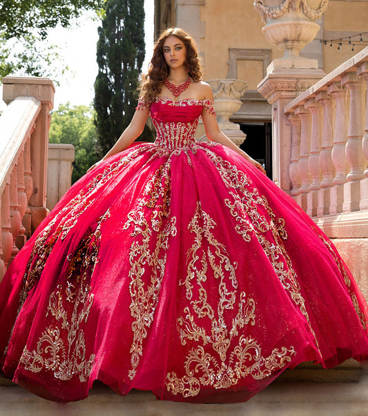 Woman in a red and gold quinceañera dress standing outdoors.