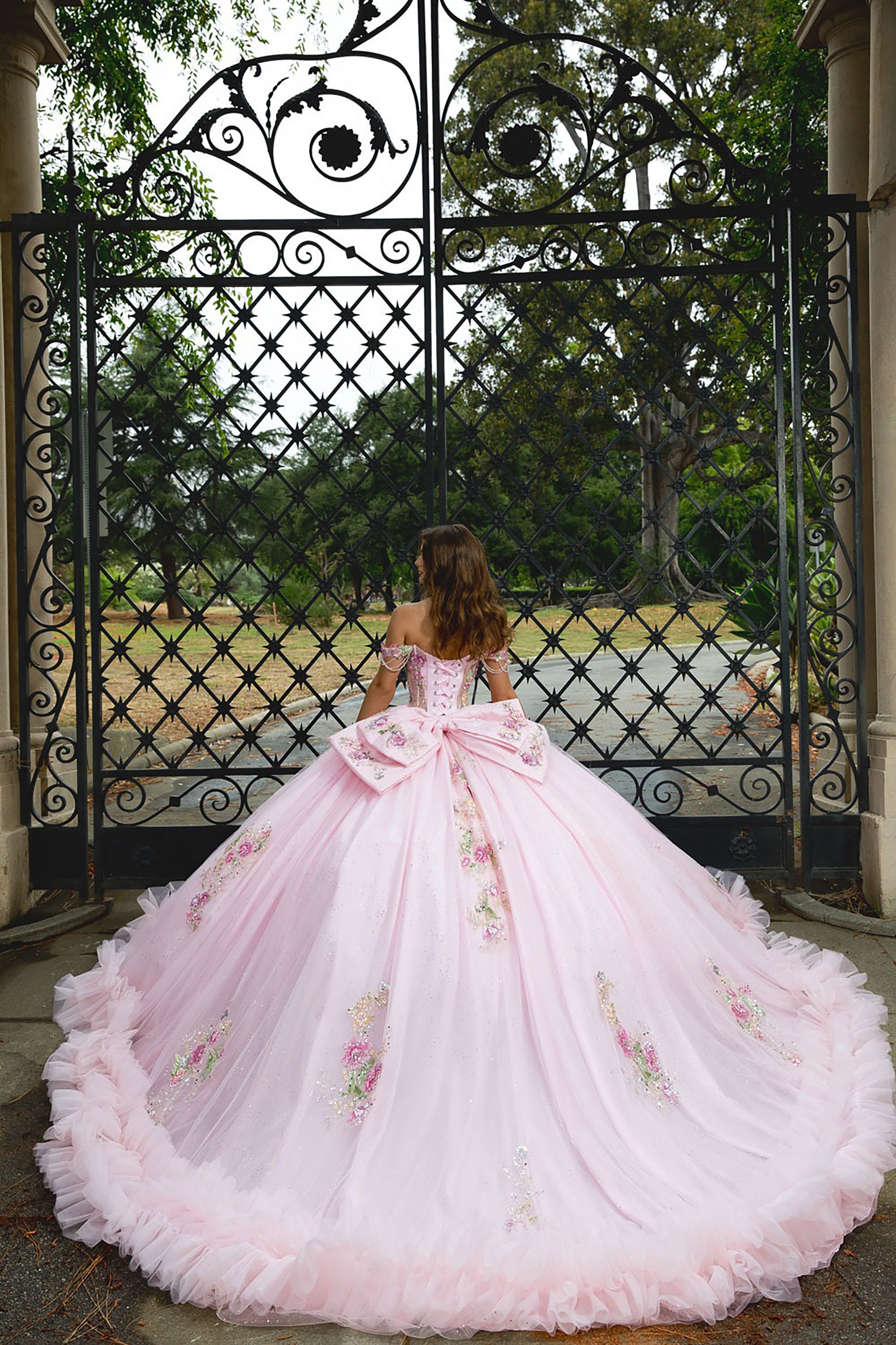 Pink floral gown in front of an ornate black gate