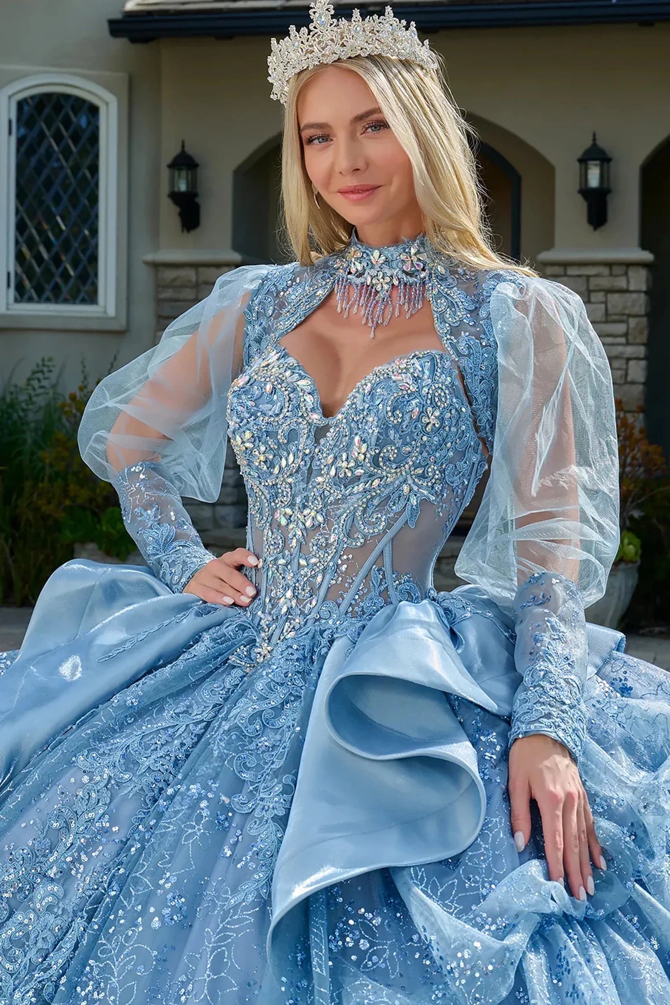 Woman in a blue, ornate dress with a matching headpiece outdoors.
