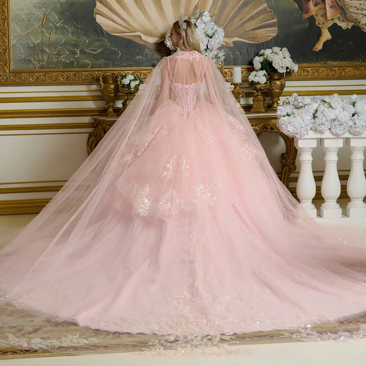 Woman in a pink ballgown dress with a long train in an elegant room with gold accents and floral arrangements.