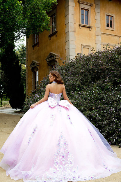 Woman in a pink and white floral gown standing in front of a building with greenery.