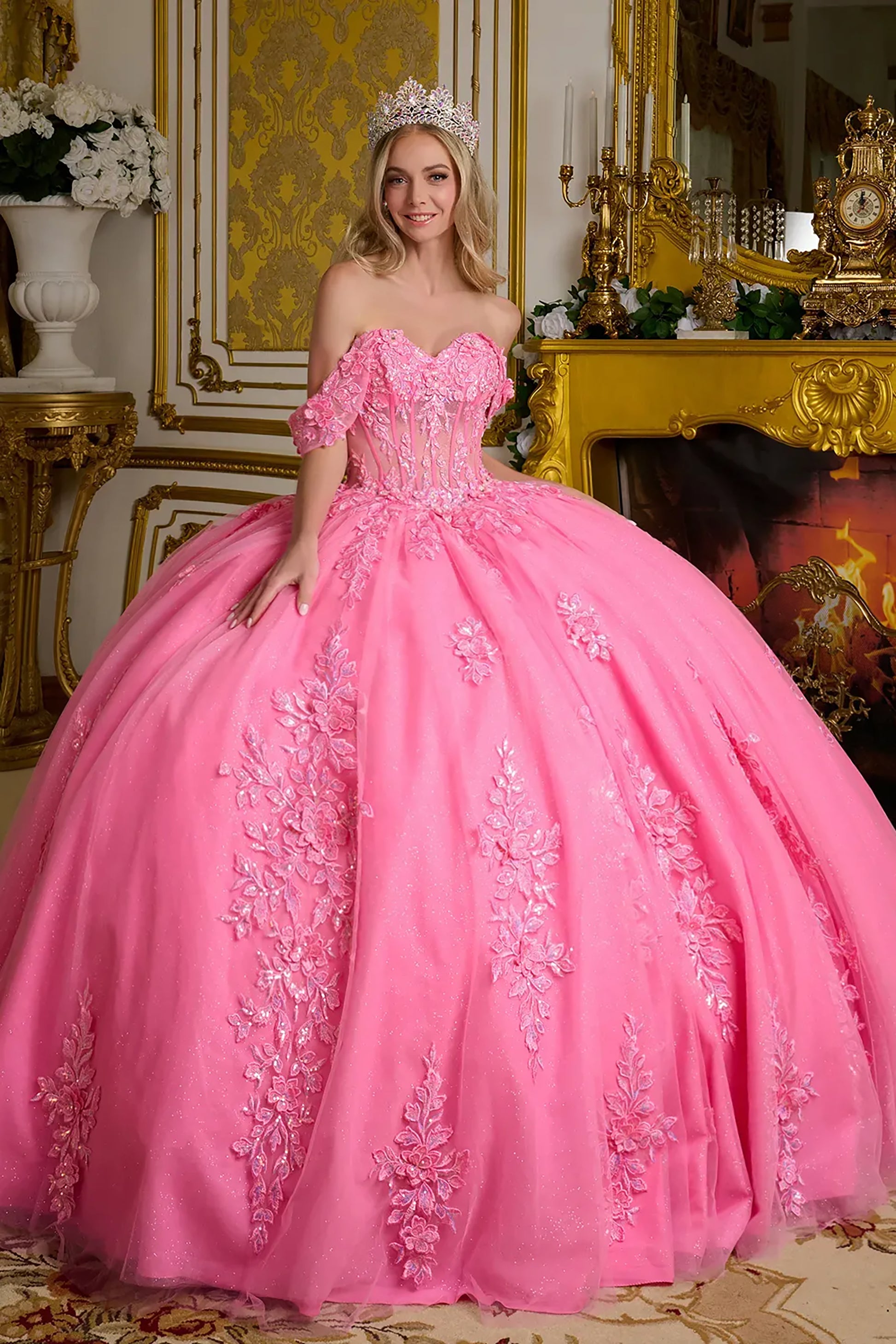 Woman in a pink ball gown with floral embroidery in an ornate room.