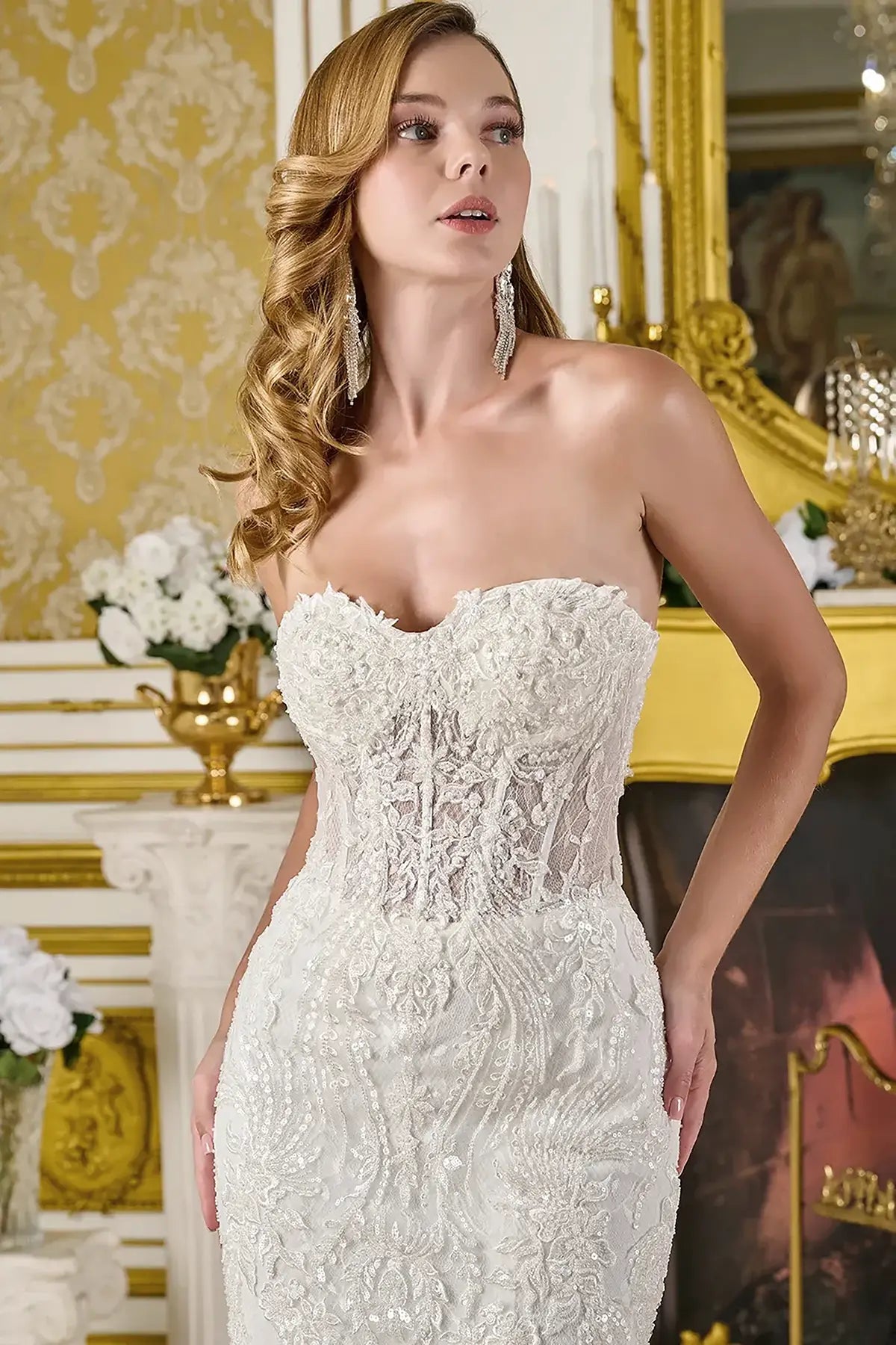Woman wearing a white strapless lace wedding  dress in an elegant interior setting.