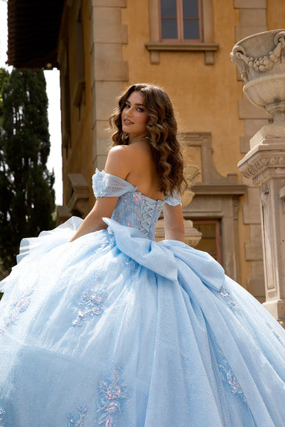 Woman in a light blue ball gown standing in front of an old building.