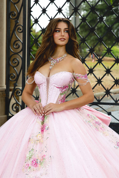 Woman in a pink floral dress standing in front of an ornate metal gate.