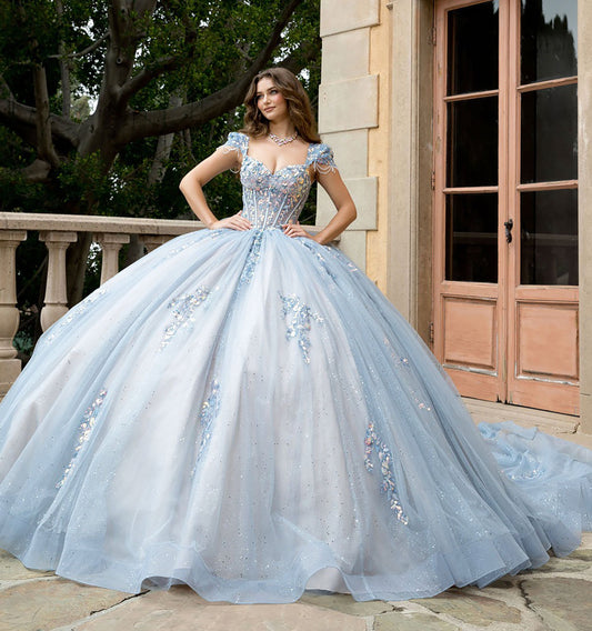 Woman in a light blue ball gown standing in front of a building with large windows.