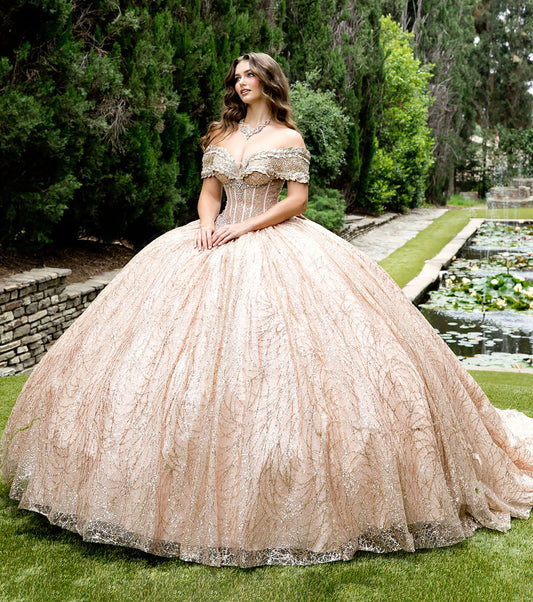 Woman in a rose gold ball gown standing in a garden with greenery and water features.