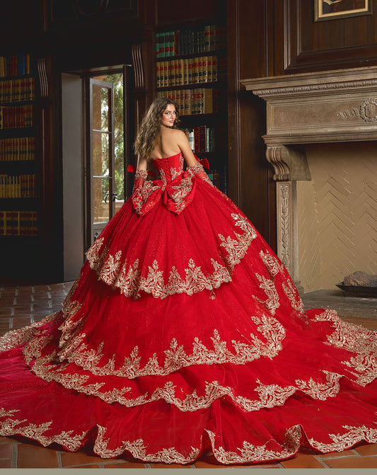 Red ball gown with gold embroidery in a room with bookshelves and a fireplace.