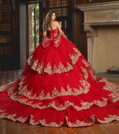 Red ball gown with gold embroidery in a room with books and a fireplace.